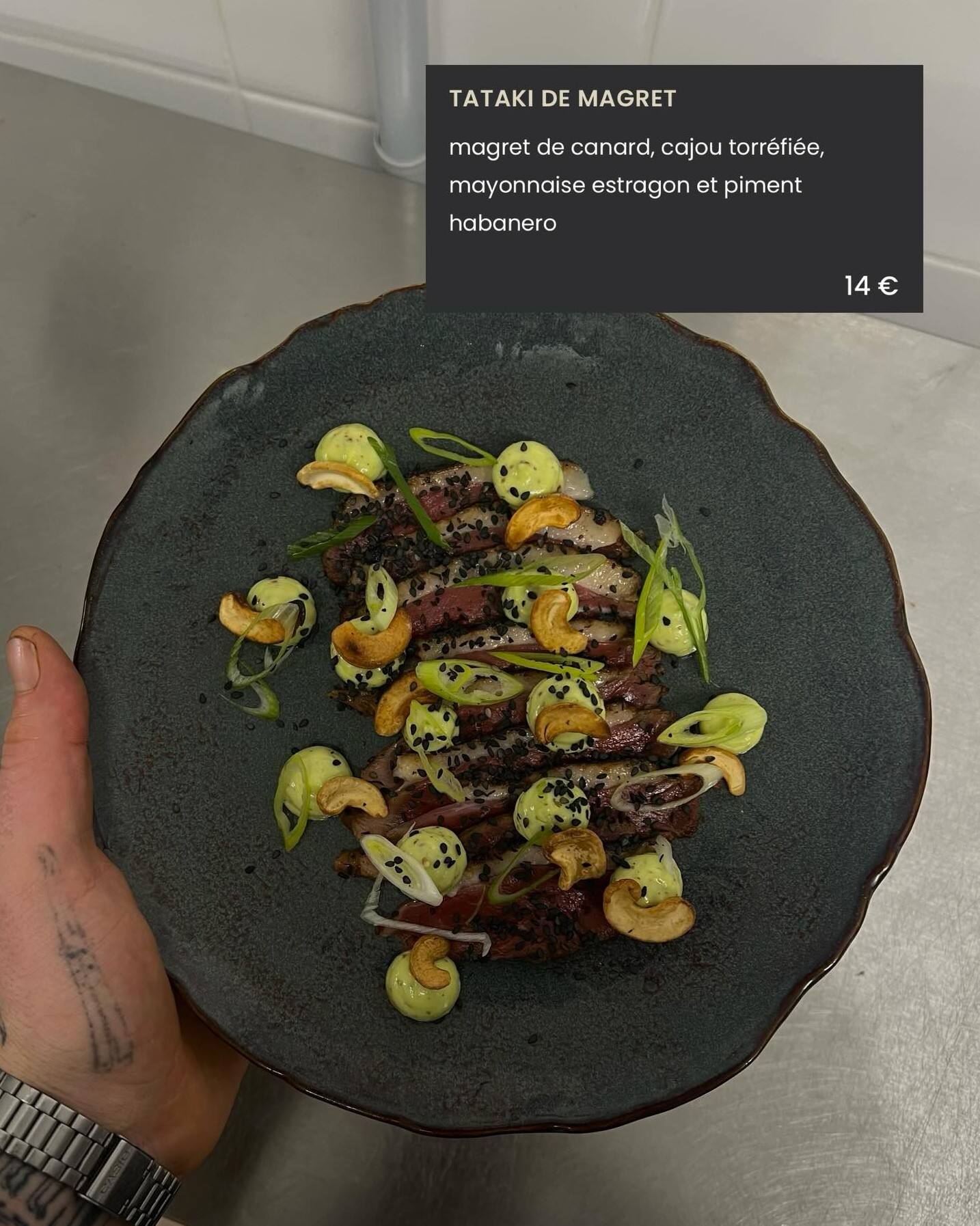 Tataki de magret tenu au-dessus du passe, avec l’intitulé de la carte incrusté : magret de canard, cajou torréfié, mayonnaise estragon et piment habanero.